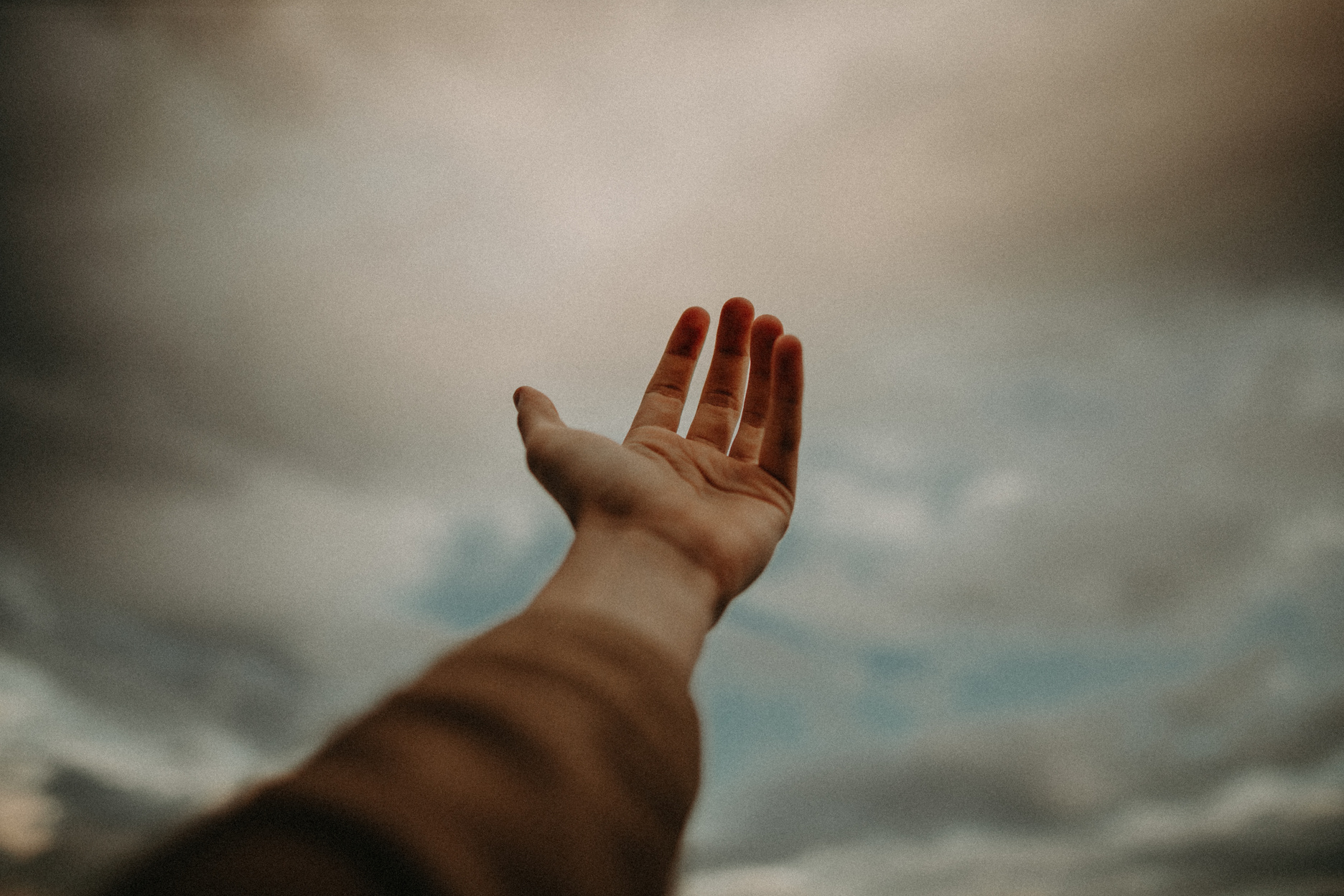 Person's Hand Reaching Out to the Sky
